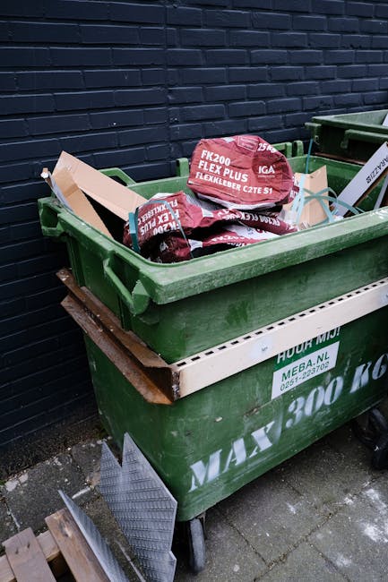 A large black waste disposal truck parked on an asphalt surface, with the company's logo and contact number visible on its side, labeled 'Heave Away Waste & Recycling'. The truck is equipped with a re